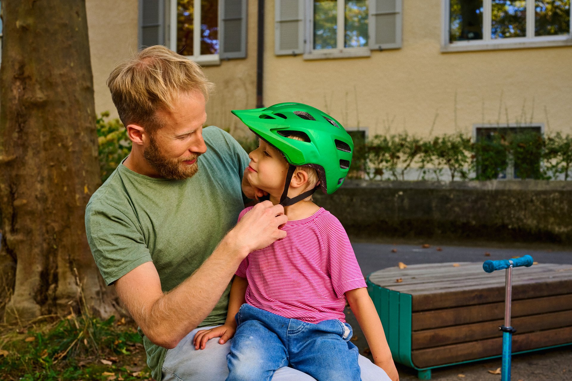 Vater zieht Sohn einen Velohelm an.